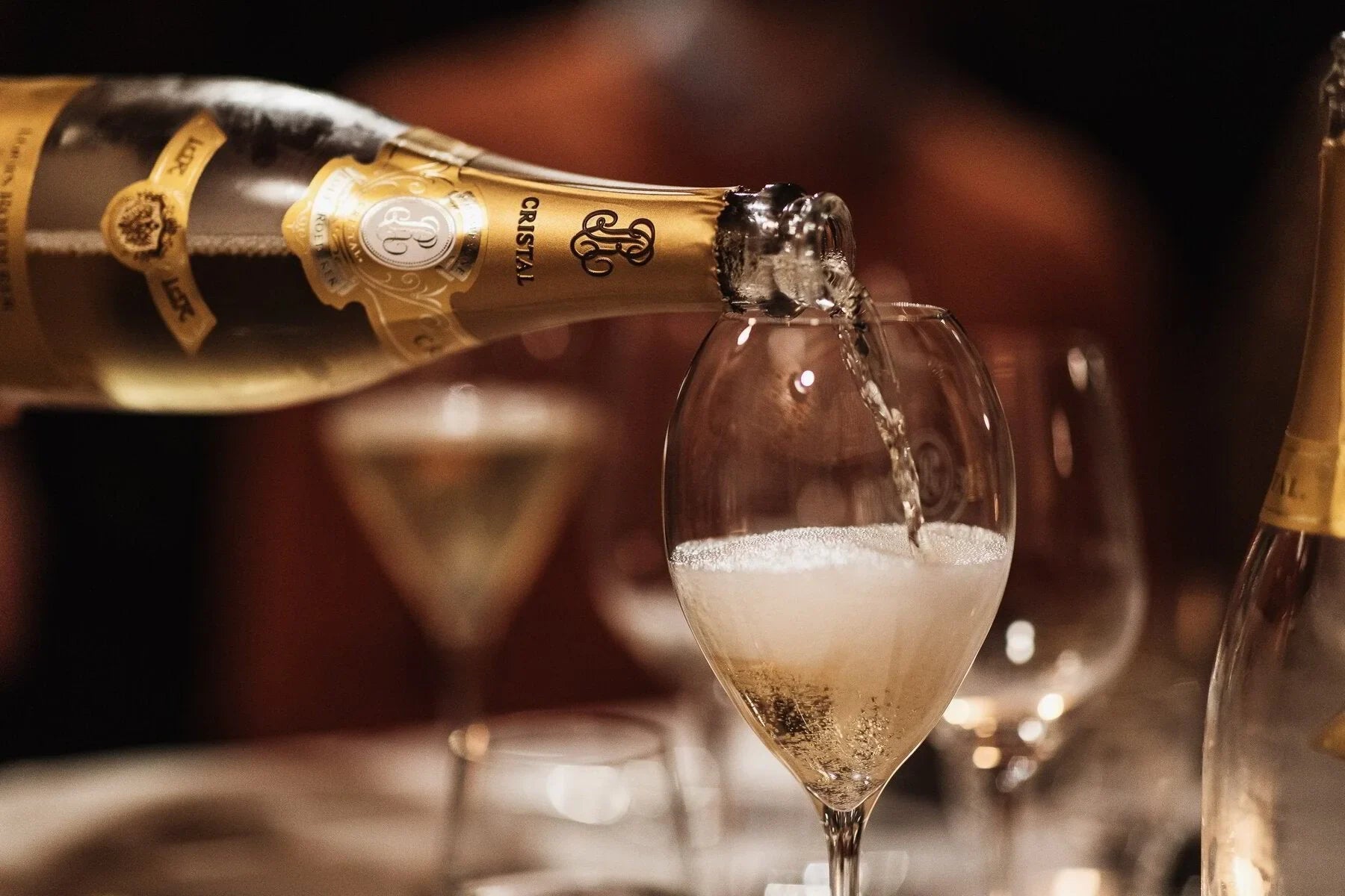 Cristal champagne being poured into a glass at an elegant dinner table