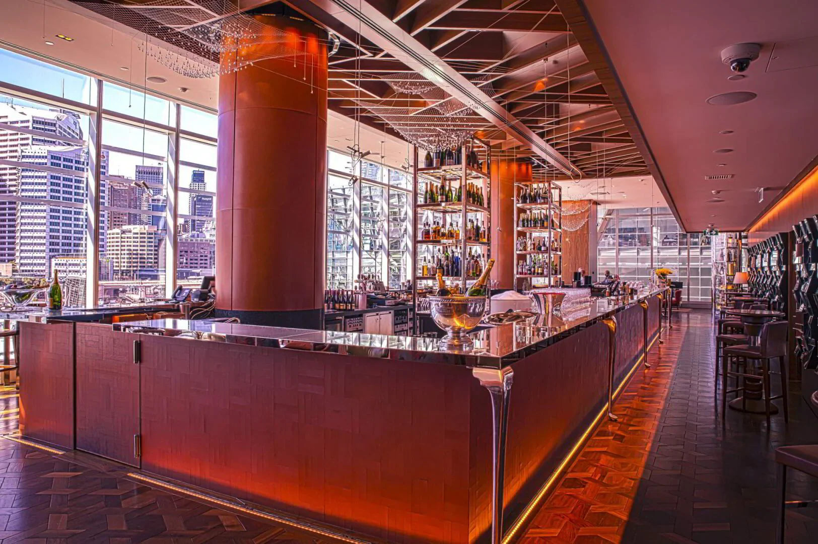 Modern champagne bar at Sofitel Darling Harbour with city skyline view, elegant decor, and bottle displays.