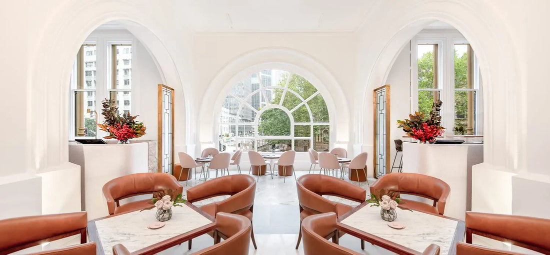 Elegant champagne bar interior with arched windows, marble tables, and brown leather chairs
