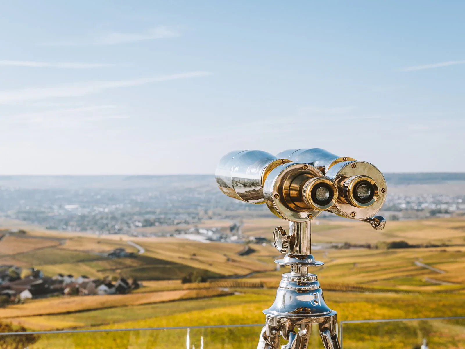 Brass telescope overlooking scenic vineyard landscape under blue sky