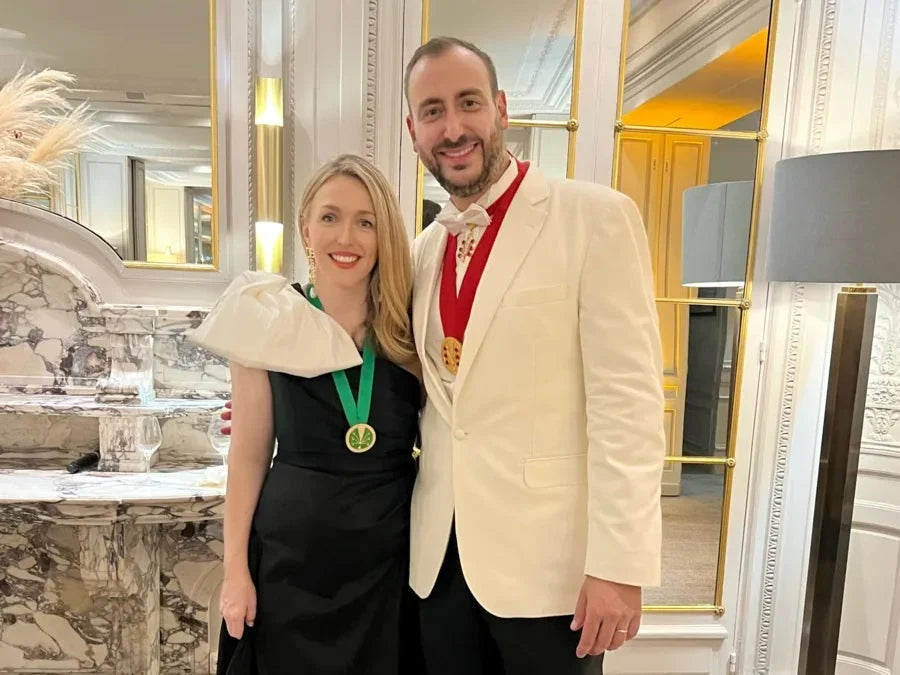 Elegant man and woman in formal attire with medals, standing in a luxurious marble room