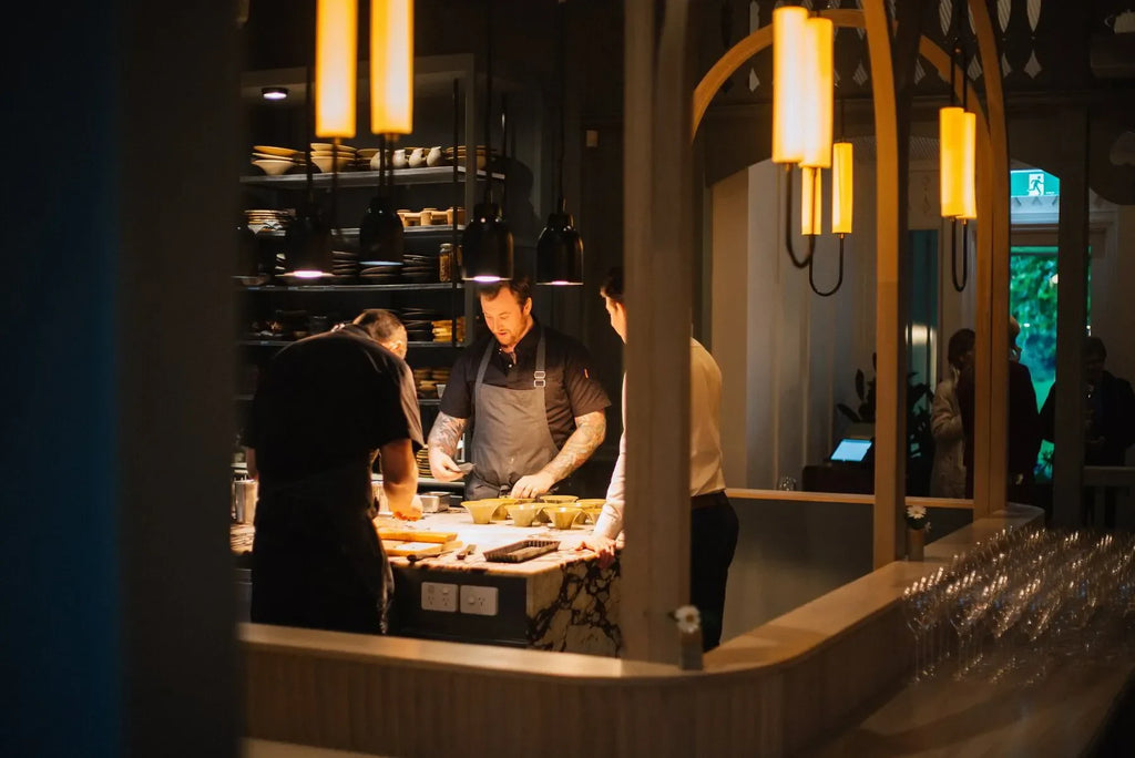 Chefs preparing dishes in modern restaurant kitchen under warm pendant lights