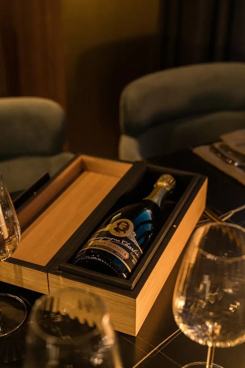 Charles Heidsieck champagne bottle in wooden box on elegant dining table with glasses
