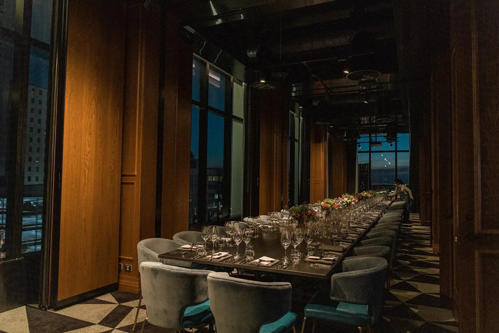 Elegant private dining room with long table set for event, city views, floral centerpieces