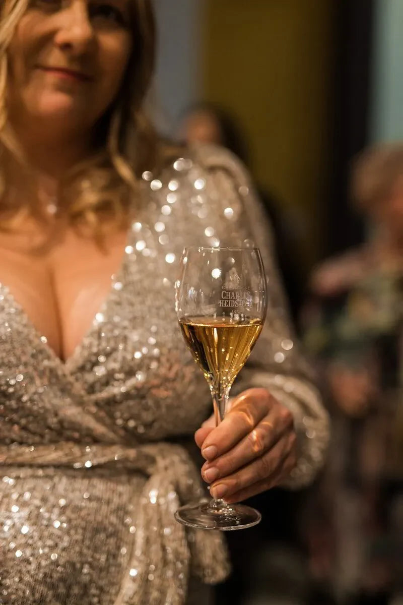 Woman in a sparkly dress holding a Charles Heidsieck champagne glass at a party