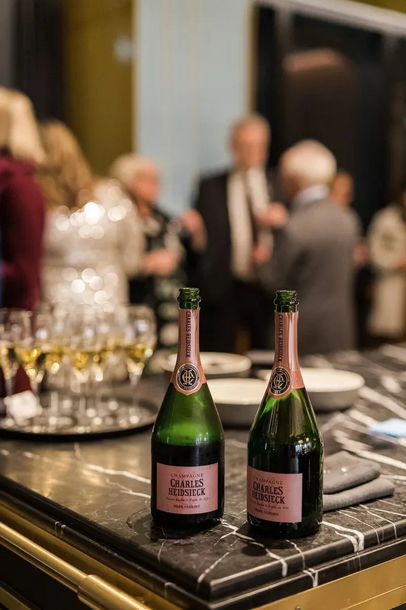 Charles Heidsieck Champagne bottles on marble counter at elegant party with people chatting