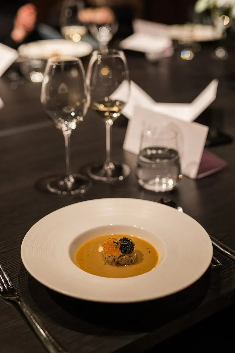 Gourmet seafood soup with caviar in a white bowl, fine dining restaurant table setting