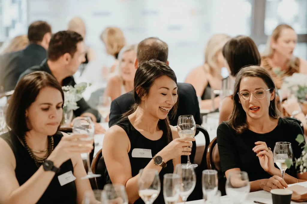 Women networking at a formal event, enjoying wine at an elegant indoor dinner party