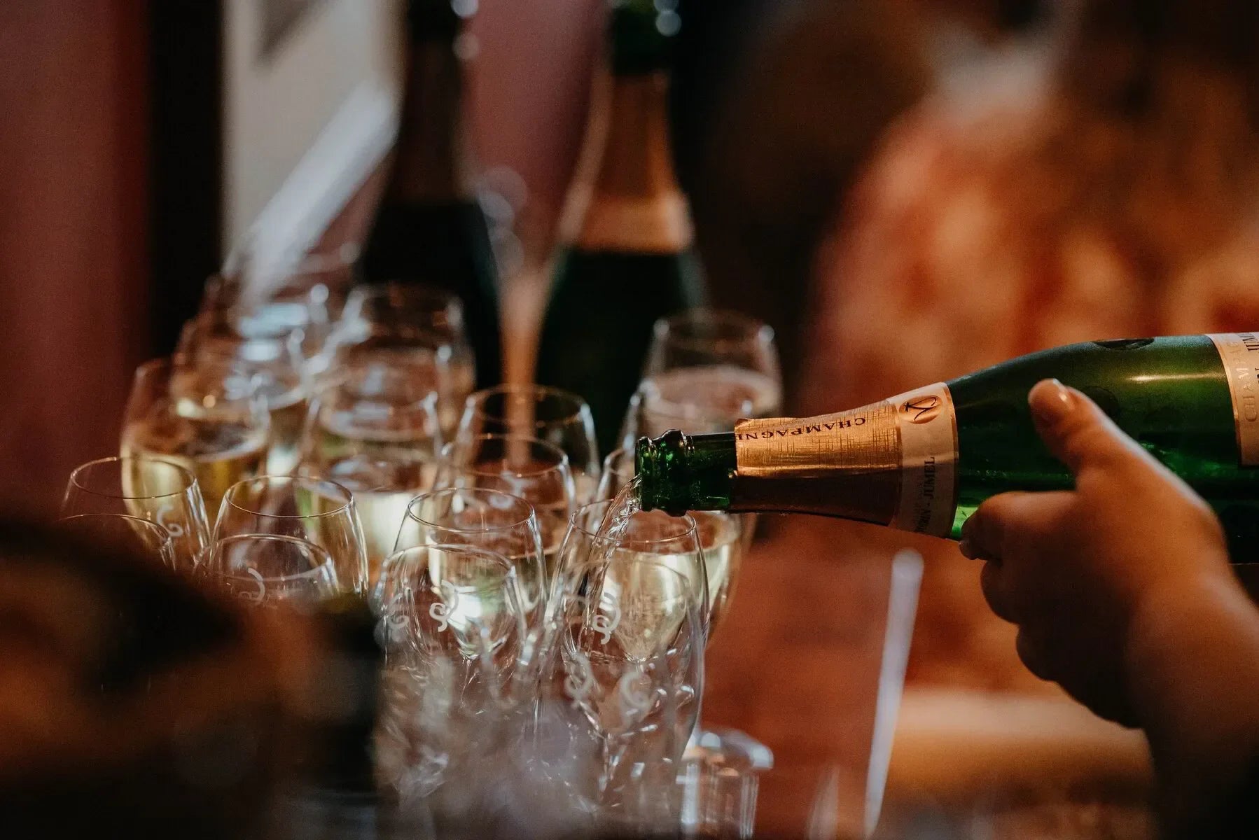 Hand pouring champagne into multiple glasses at a festive celebration