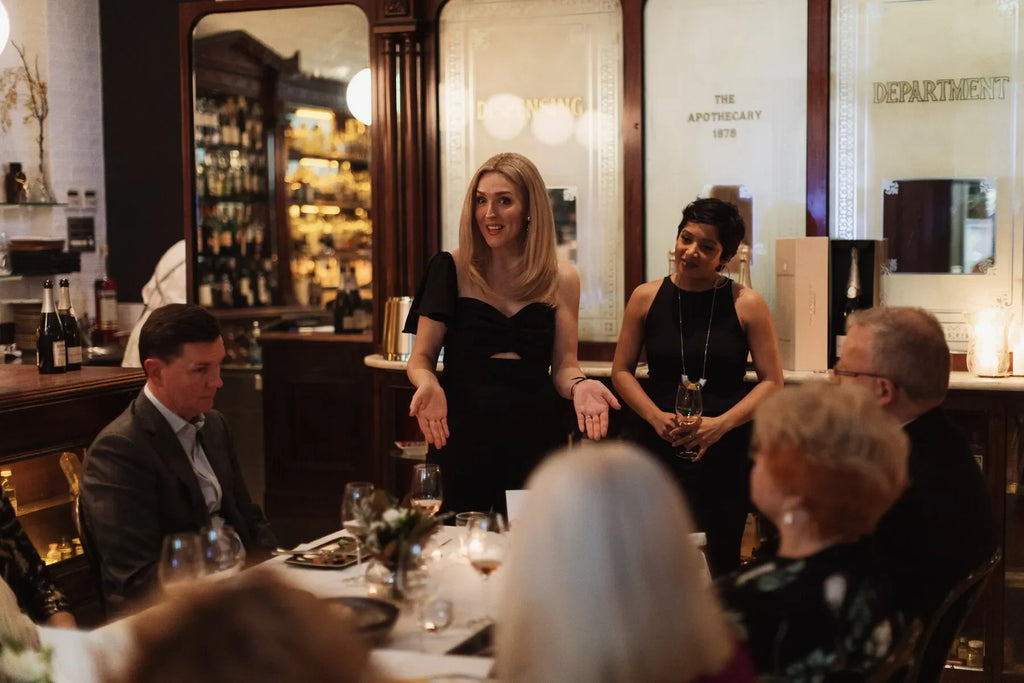 Elegant dinner party with people socializing at upscale restaurant, woman speaking at table