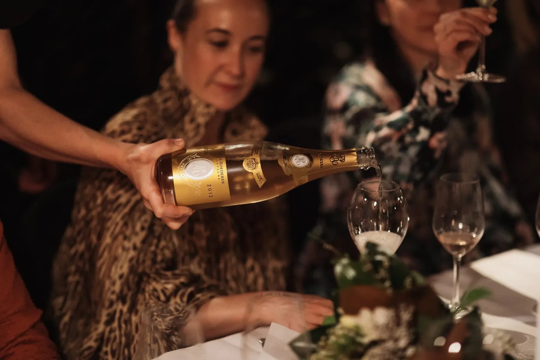 Cristal champagne bottle being poured into a wine glass at elegant dinner party