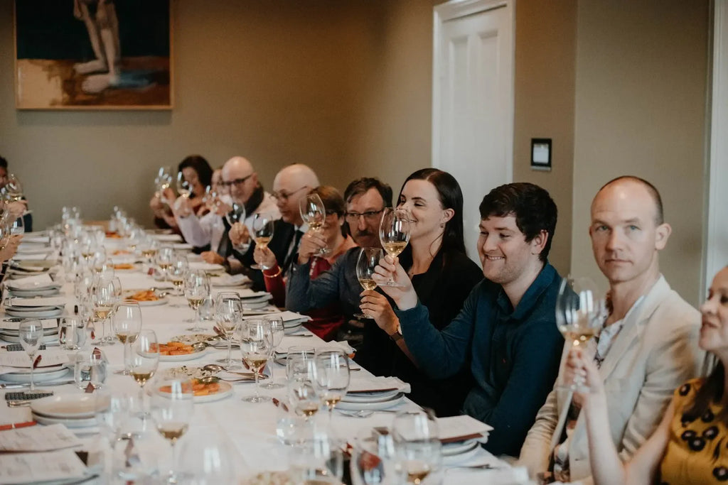 Group of people enjoying wine tasting at a long dining table in a restaurant