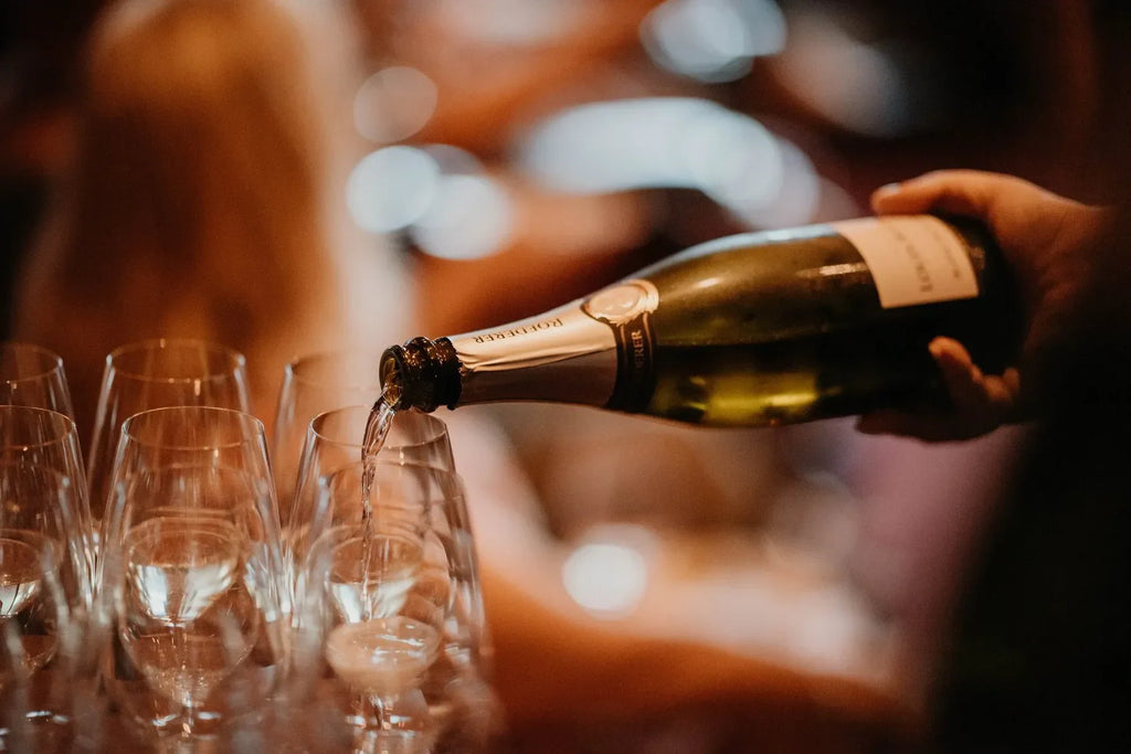 Hand pouring sparkling wine into champagne glasses at a celebration event