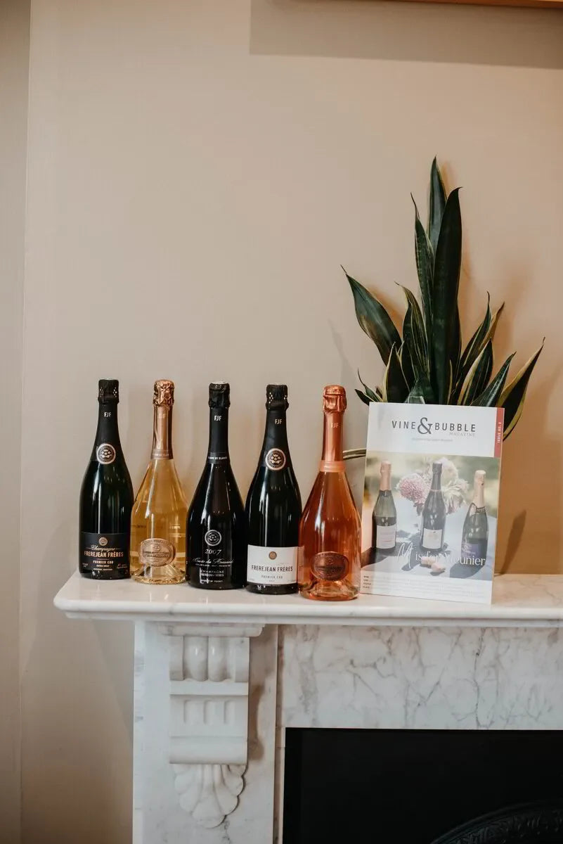 Five Frerejean Frères champagne bottles and Vine & Bubble magazine on marble mantle