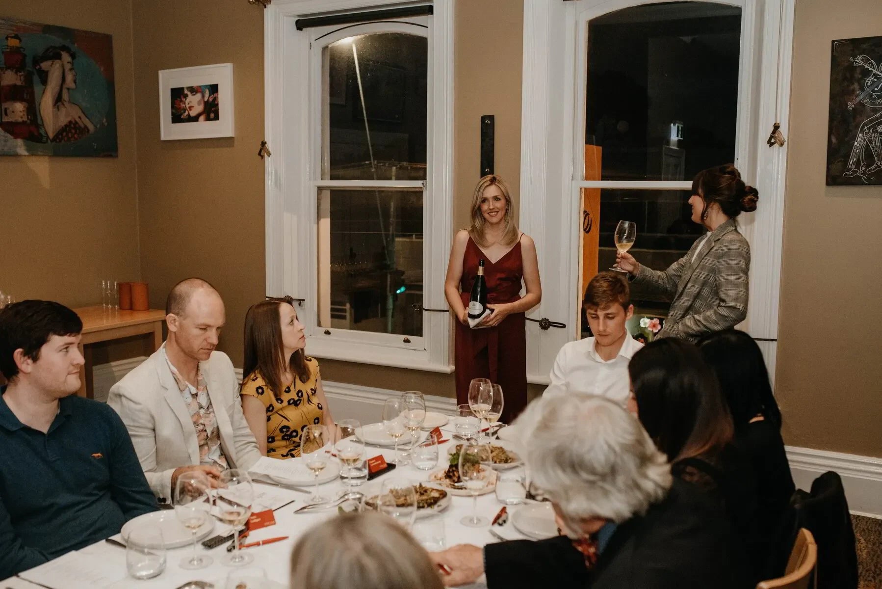 Group enjoying wine dinner in elegant dining room with artwork and large windows