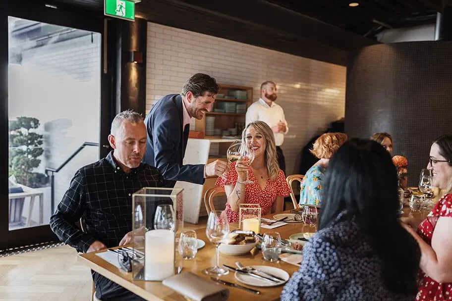 Group enjoying a wine tasting at a restaurant launch event, modern dining setting