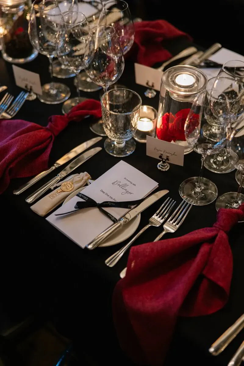 Elegant tablescape featuring a Bollinger Champagne dinner setting with wine glasses, cutlery, and branded event materials.