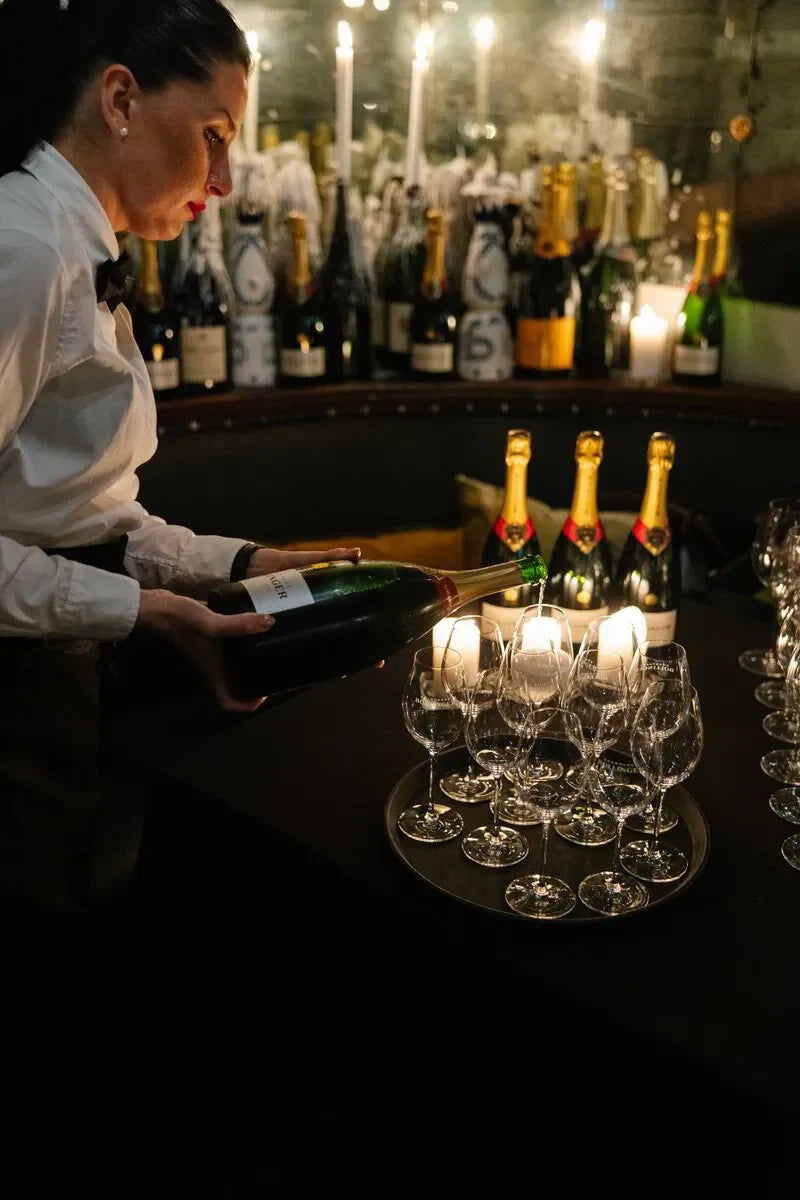 Woman pouring Bollinger champagne into glasses, caviar dinner event setting, Sydney October 2024.