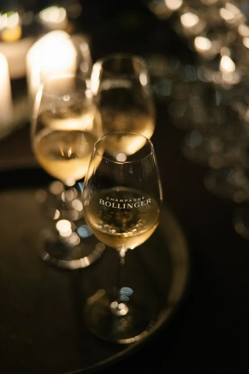 Elegant Bollinger Champagne dinner: Sparkling wine glasses reflecting ambient lighting. Celebratory atmosphere.