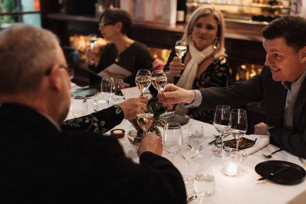 Elegant dinner party with four adults toasting champagne at a candlelit restaurant table