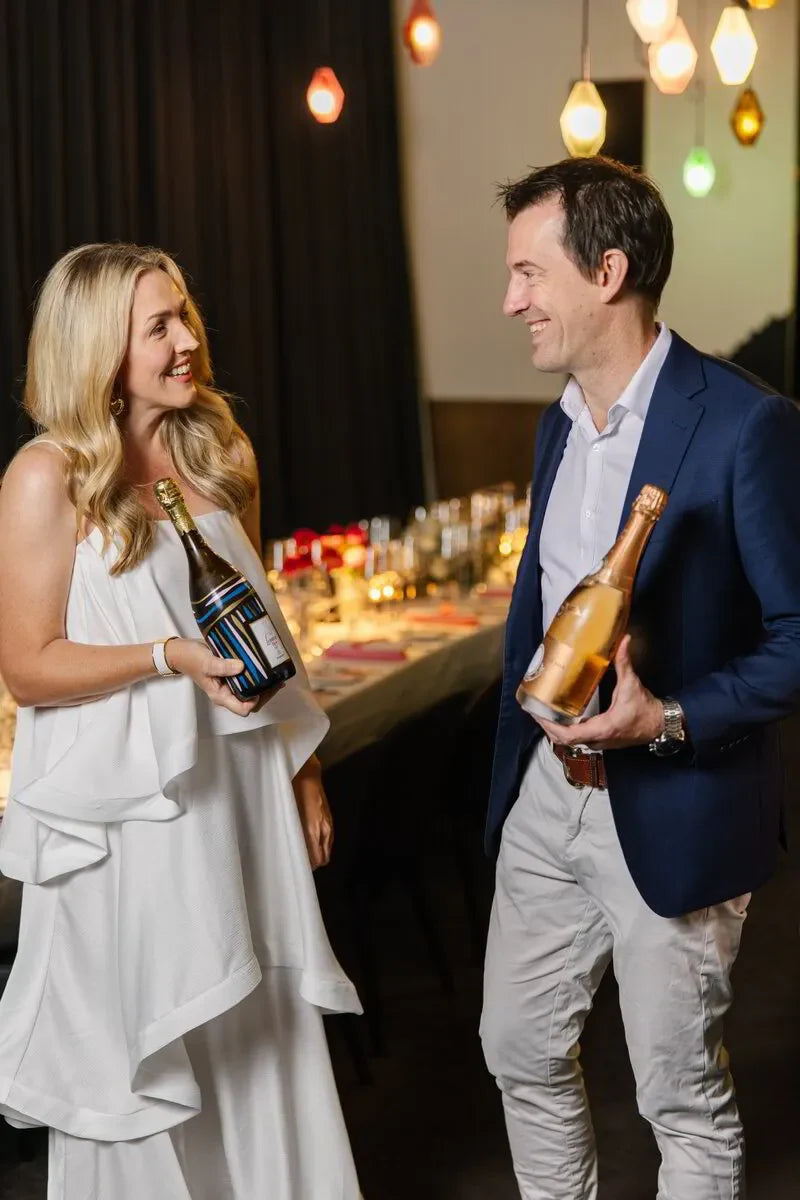 Attendees smiling while holding rosé champagne bottles at The Ultimate Rosé Champagne Dinner in Sydney, March 2025.