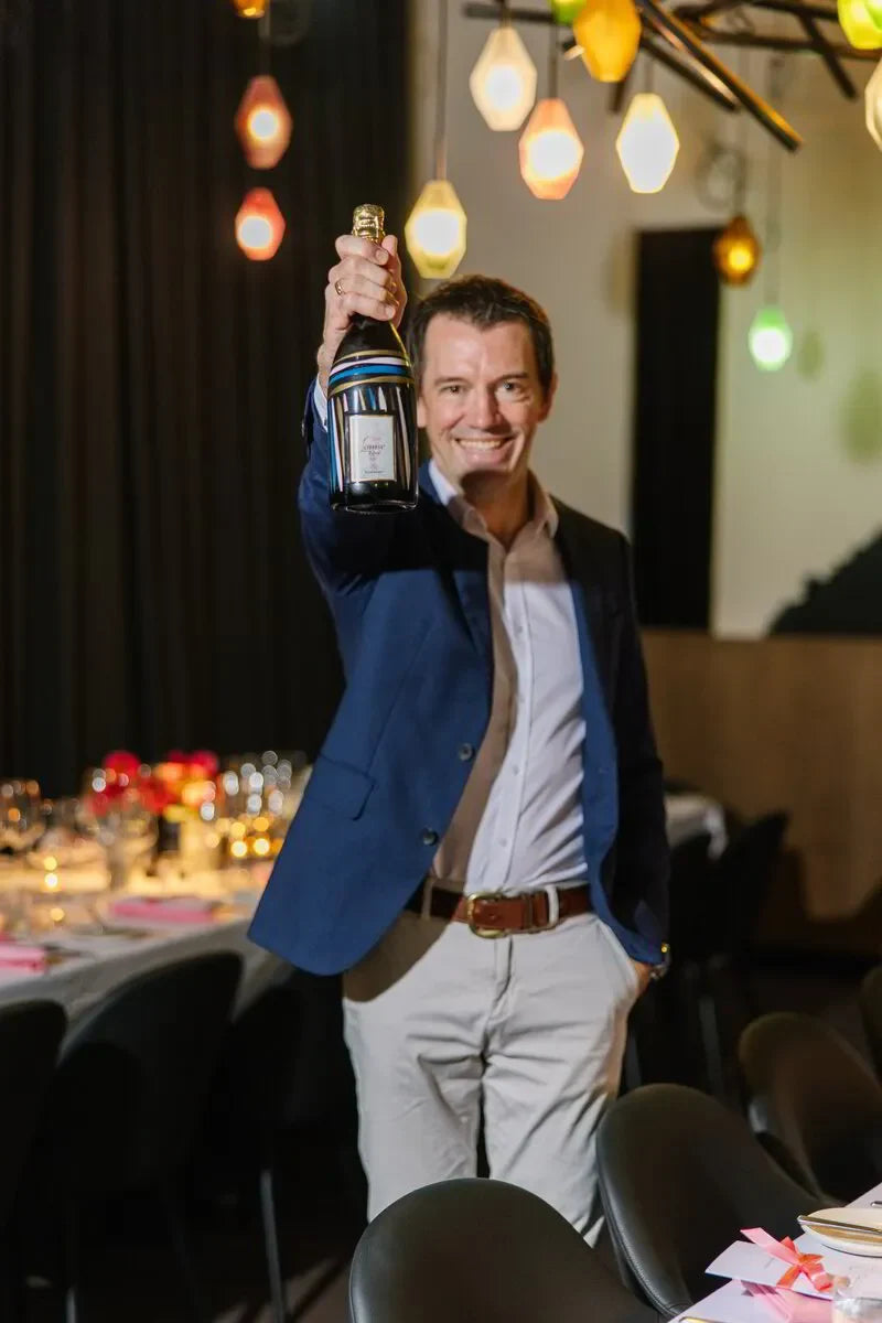 Man holding up bottle of rosé champagne celebrating a champagne dinner event.