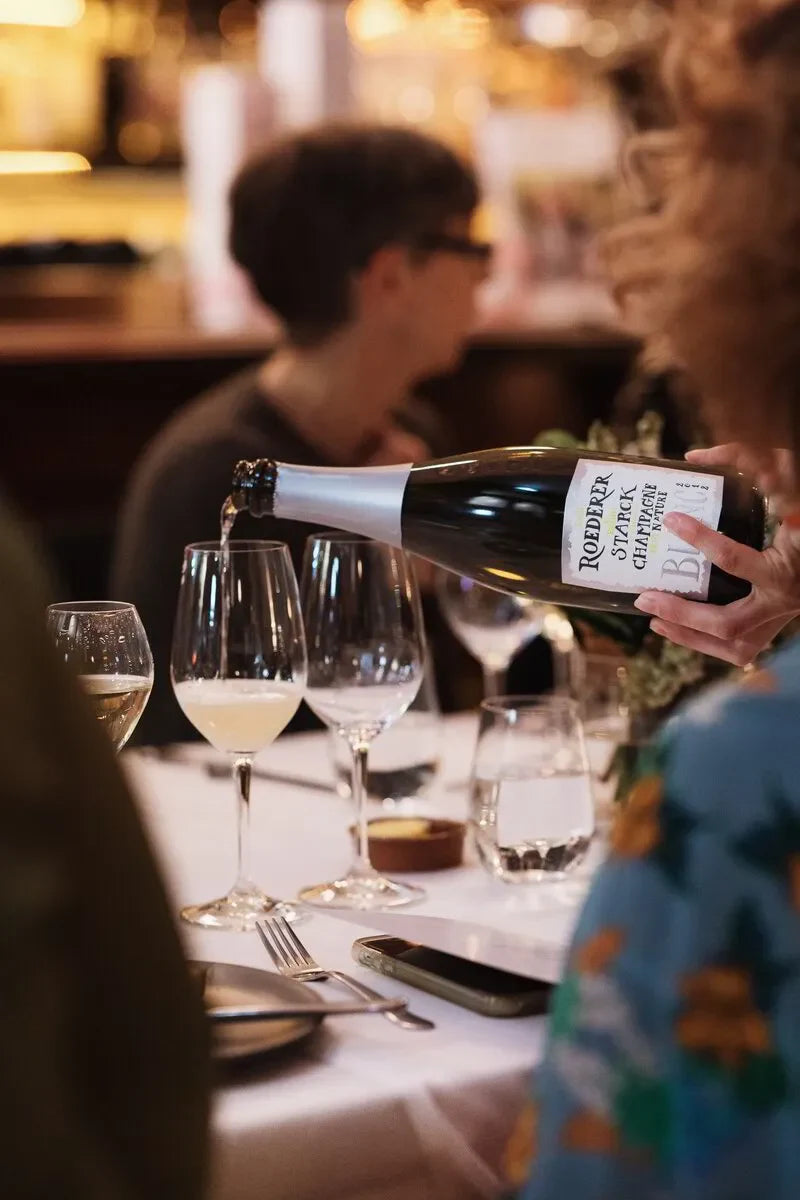 Pouring Roederer champagne into wine glasses at elegant dinner table setting