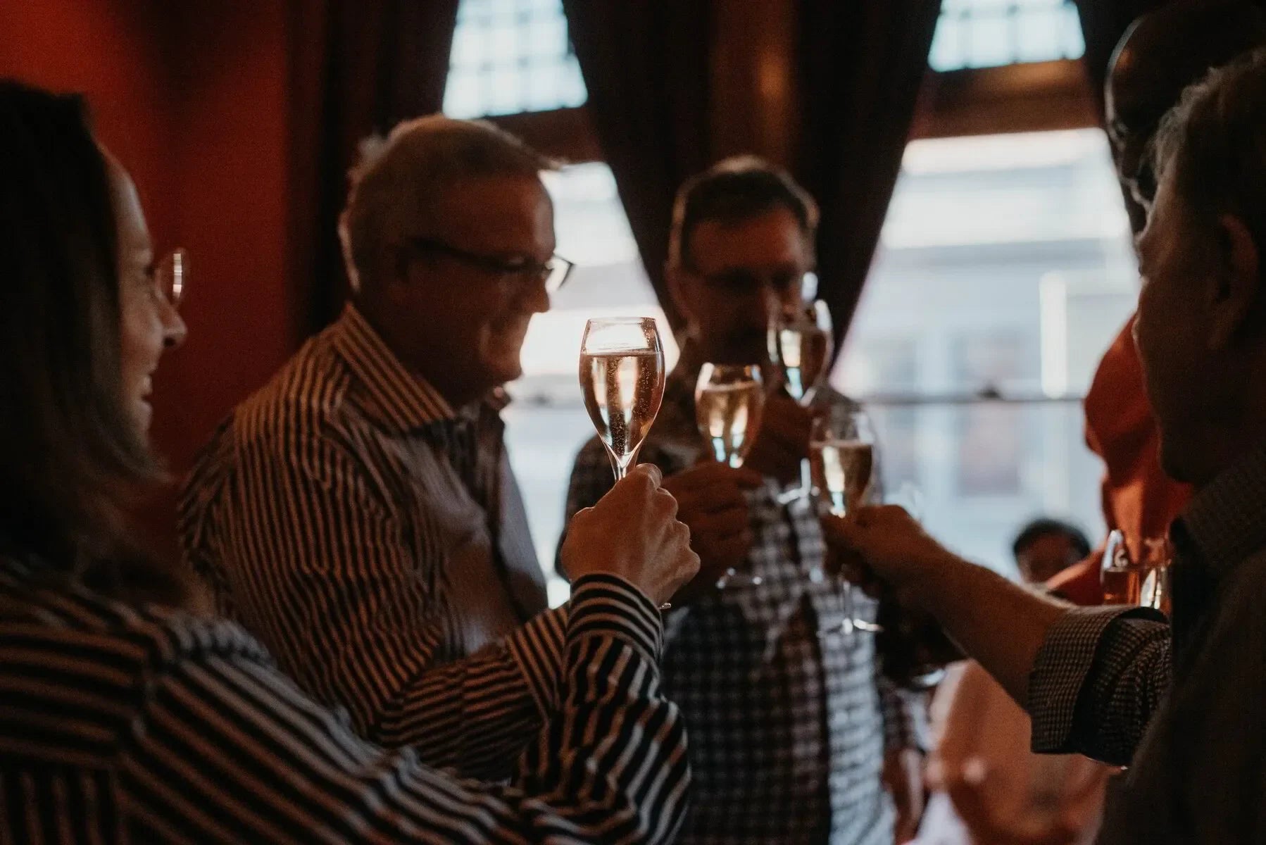 Group of people toasting with champagne glasses in a warmly-lit indoor setting