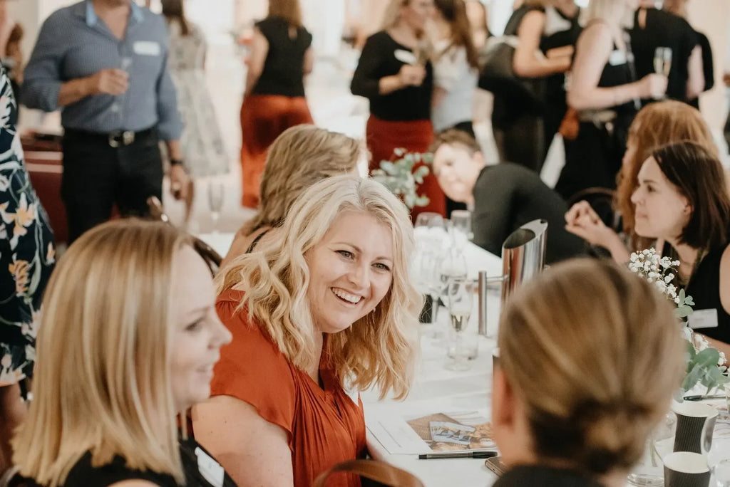 Women networking and smiling at an indoor business event or conference table