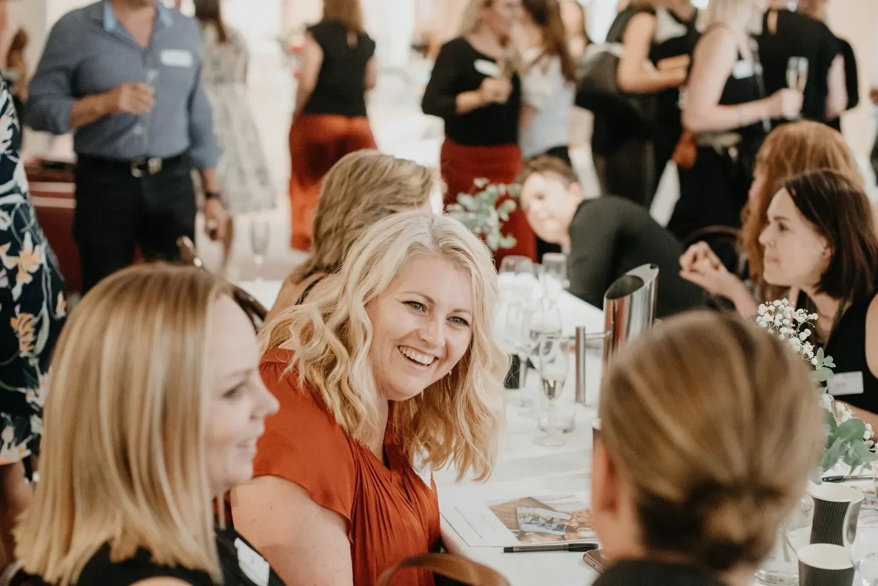 Women networking and smiling at an indoor business event or conference table