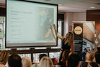 Woman leading a Champagne Foundations Course presentation with map and text projected in a bright modern room