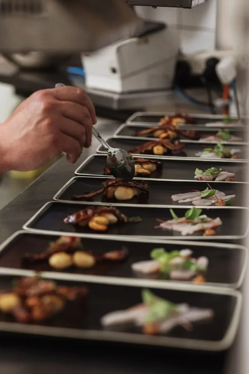 Chef plating gourmet dinner dishes in a restaurant kitchen for fine dining event