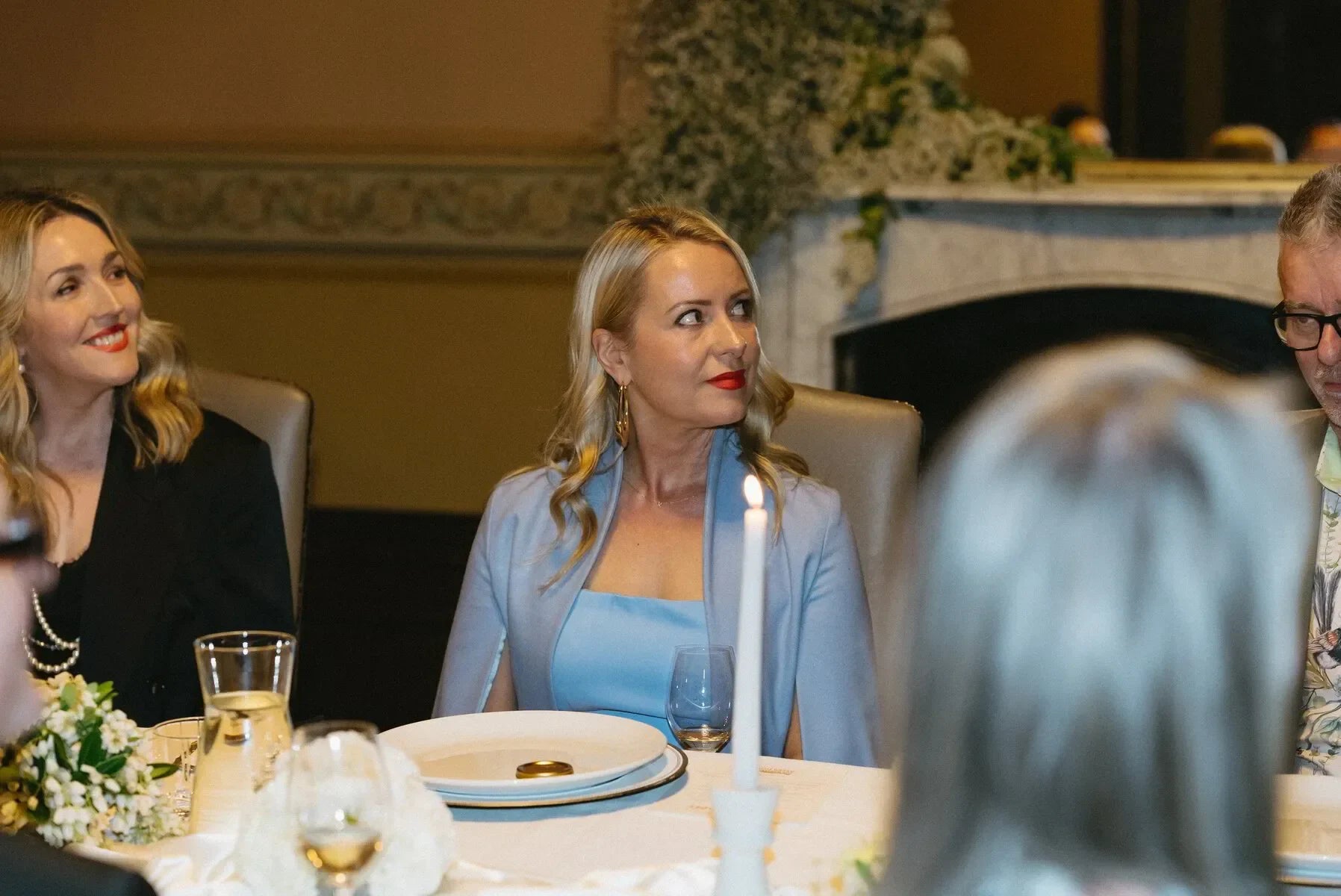 Elegant dinner party with women in formal attire seated at a candlelit table