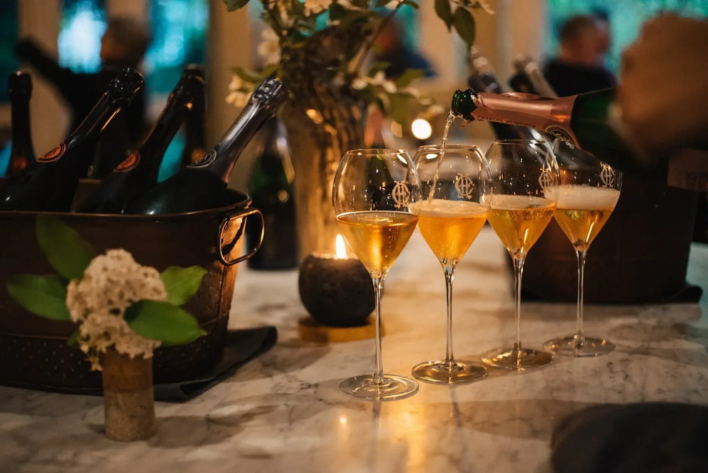 Champagne glasses being filled on marble table with chilled bottles and candlelight