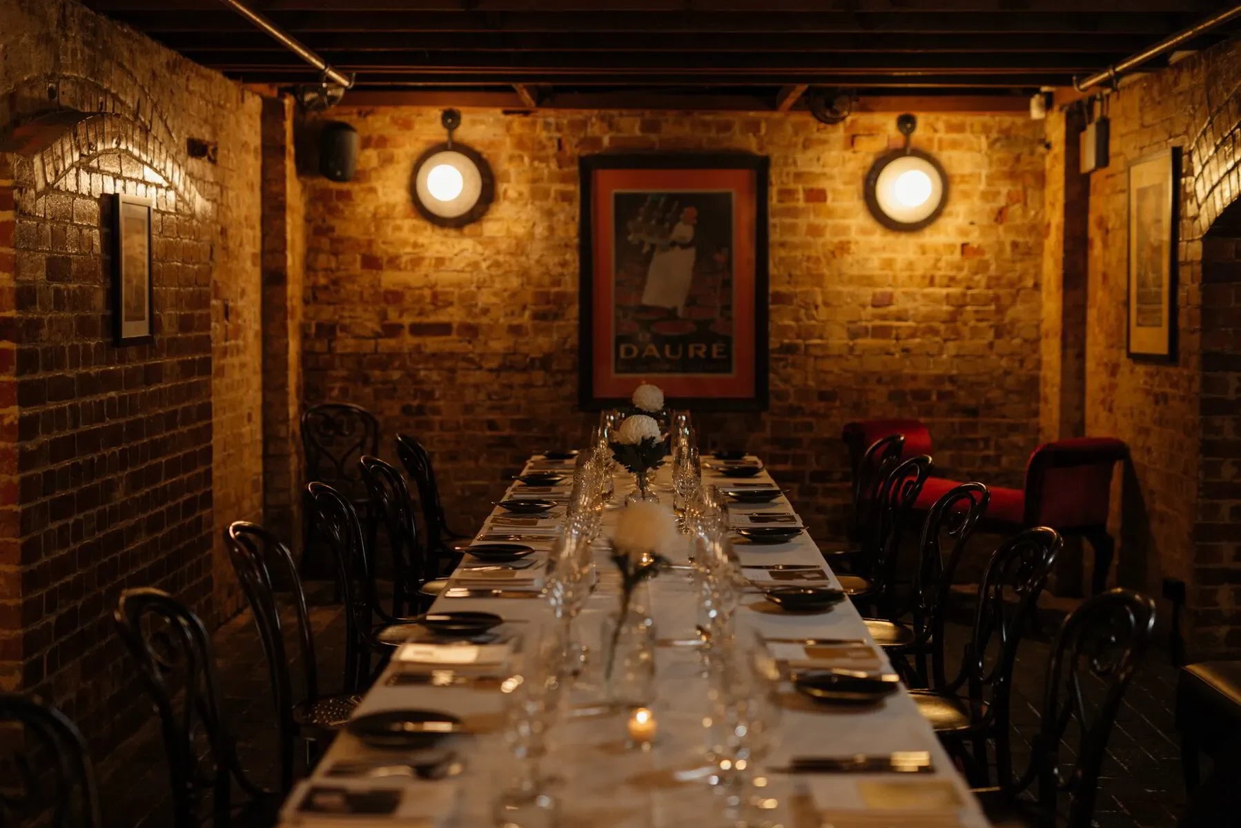 Long formal dining table set for dinner in a rustic brick-walled private dining room