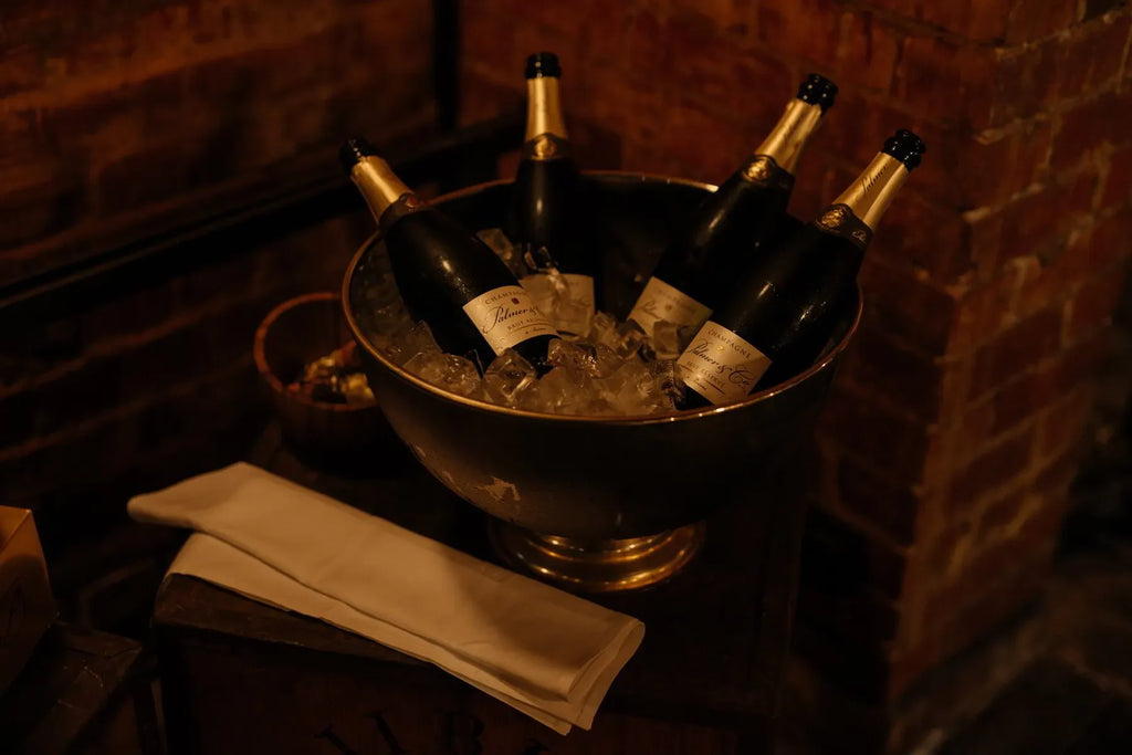 Four champagne bottles chilling in an ice bucket against a rustic brick wall ambiance.