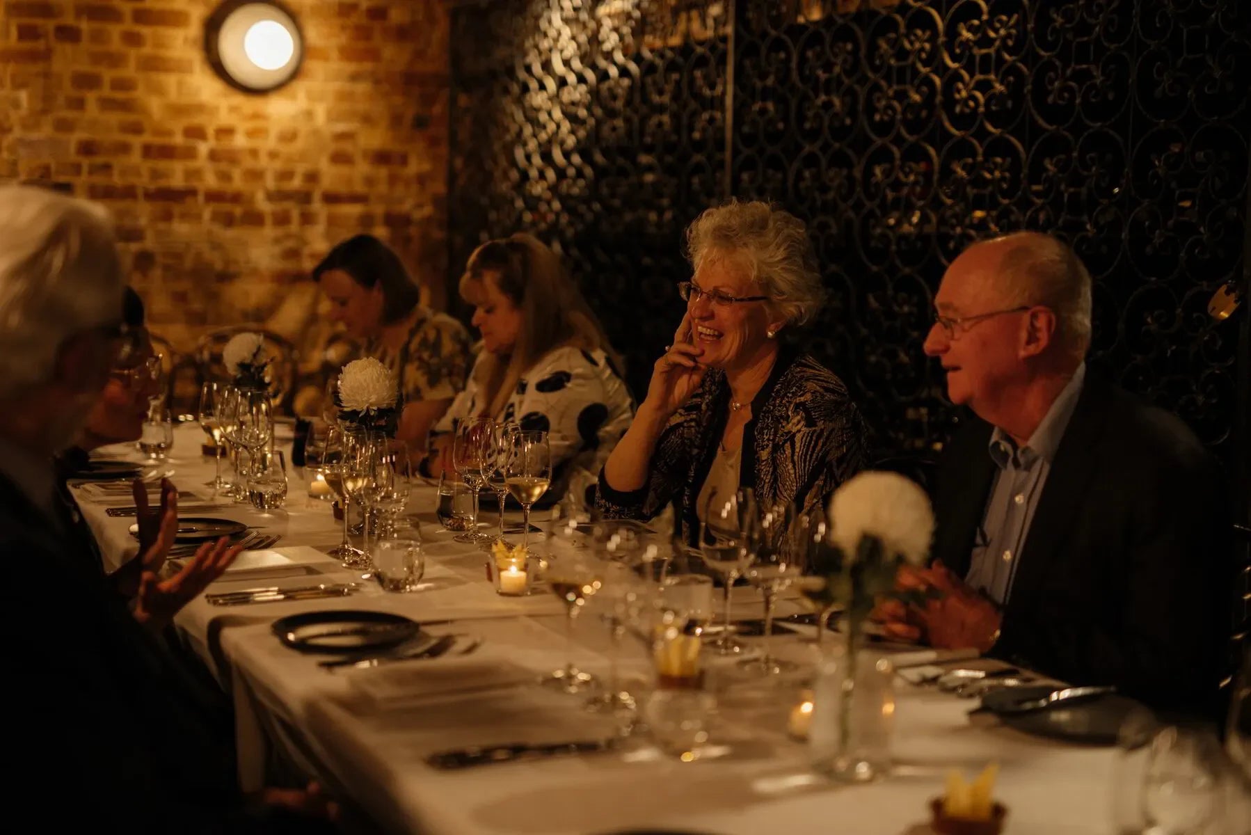Elegant dinner party in a cozy, dimly lit restaurant with guests enjoying conversation