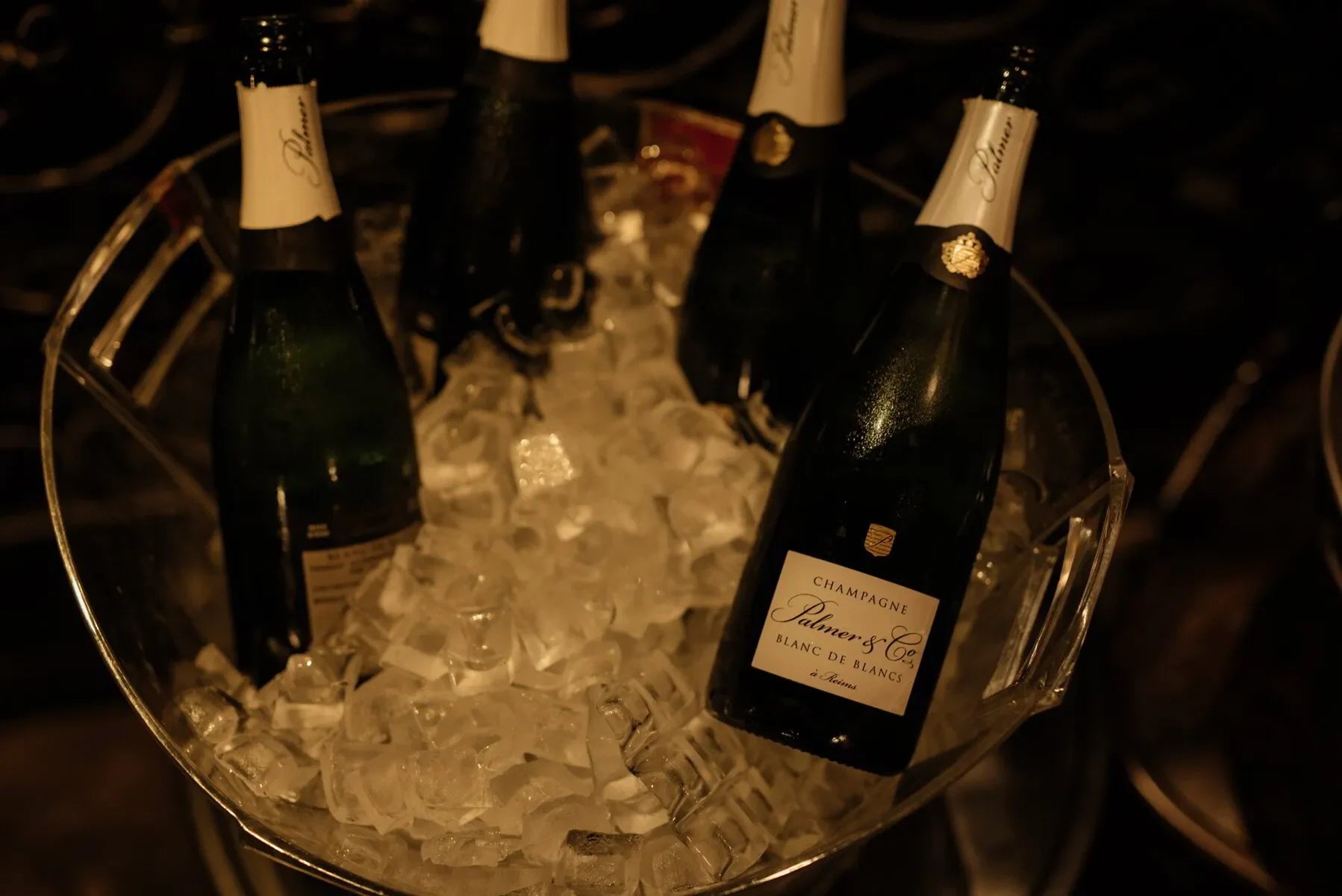 Bottles of Palmer & Co Champagne chilling in a clear ice bucket, luxury beverage setting