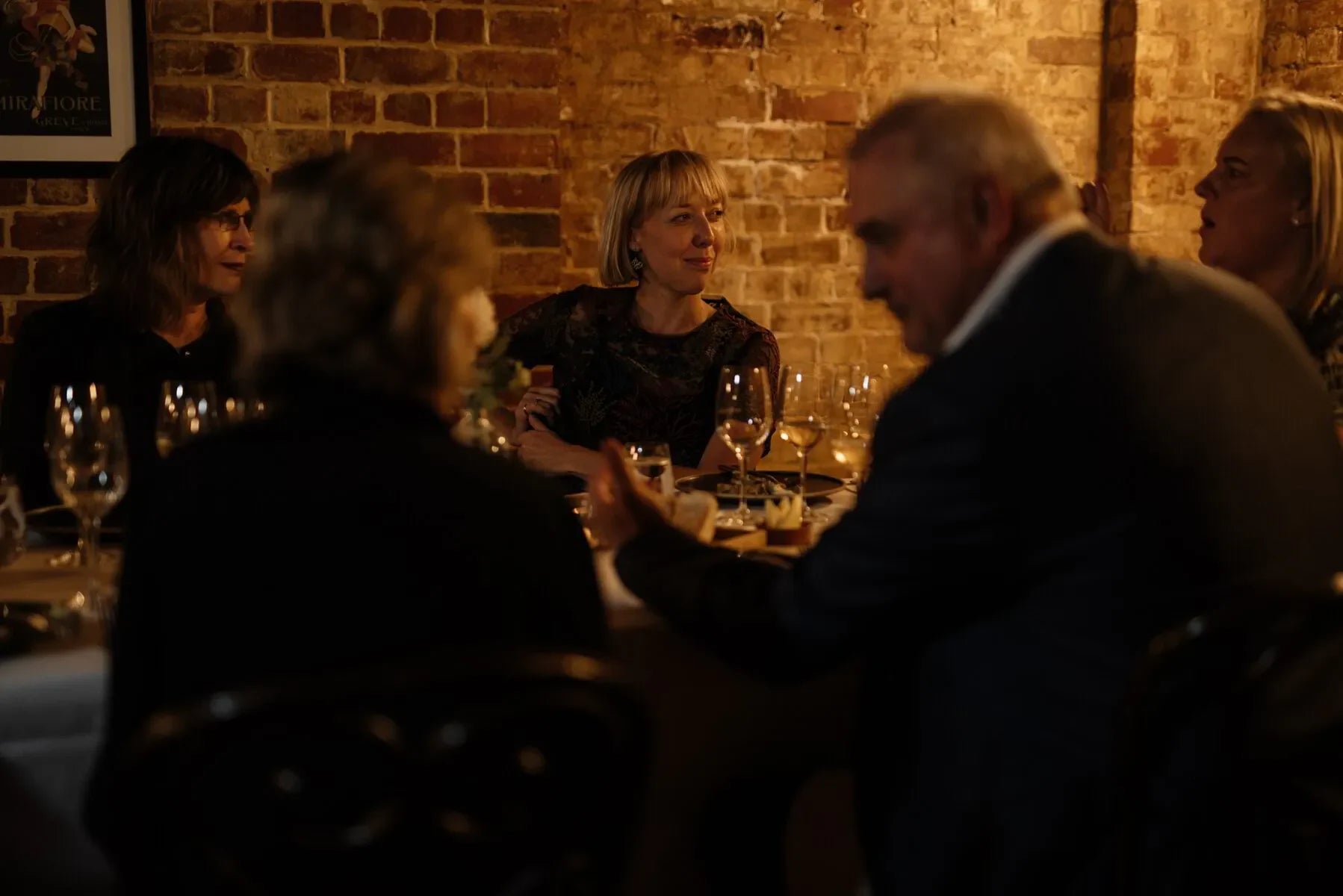 Group dining at a cozy restaurant with exposed brick walls and wine glasses on the table