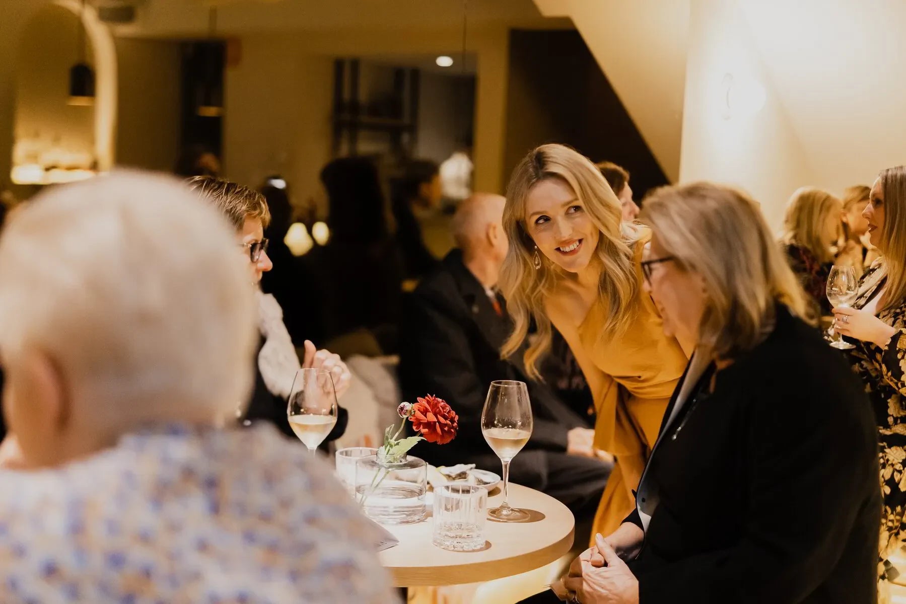Elegant group enjoying wine at a stylish restaurant table with flower centerpiece