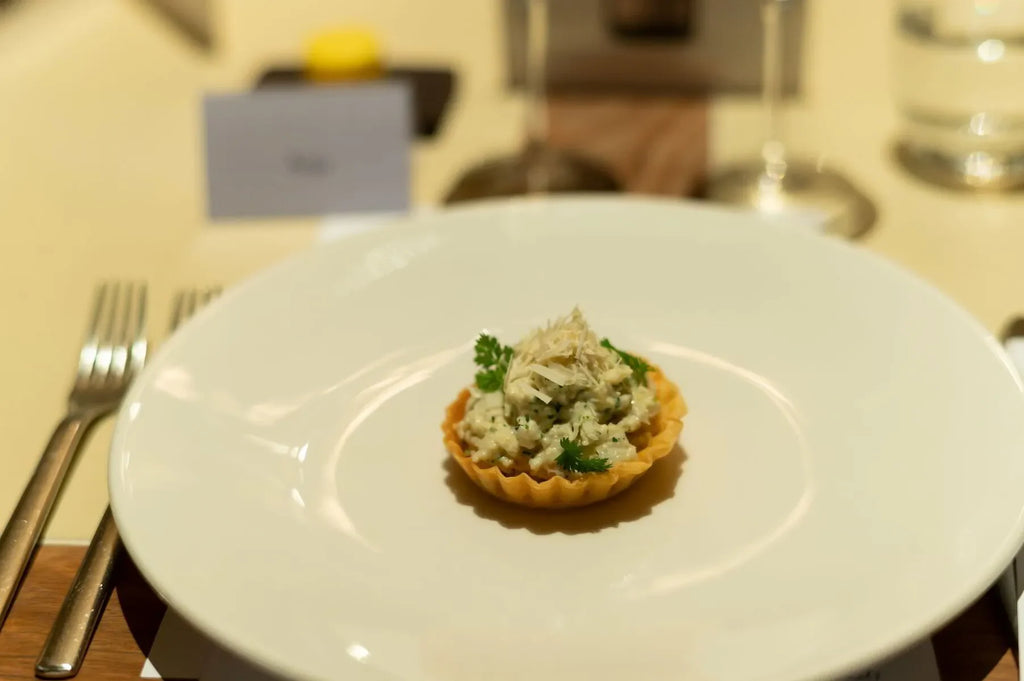 Gourmet savory tart with creamy filling and herbs on white plate at elegant table setting