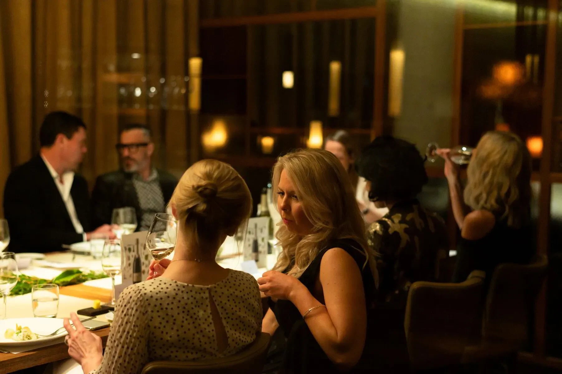 Elegant dinner party with people enjoying wine in a softly lit upscale restaurant