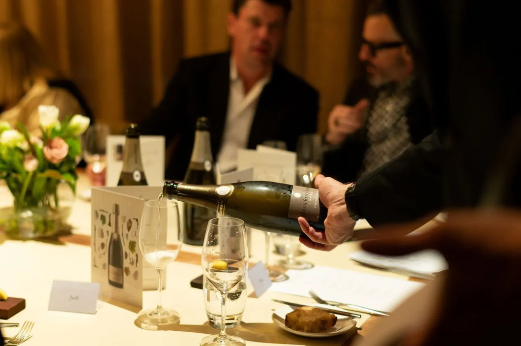 Louis Roederer Collection 242 champagne bottle being poured at an elegant dinner table.