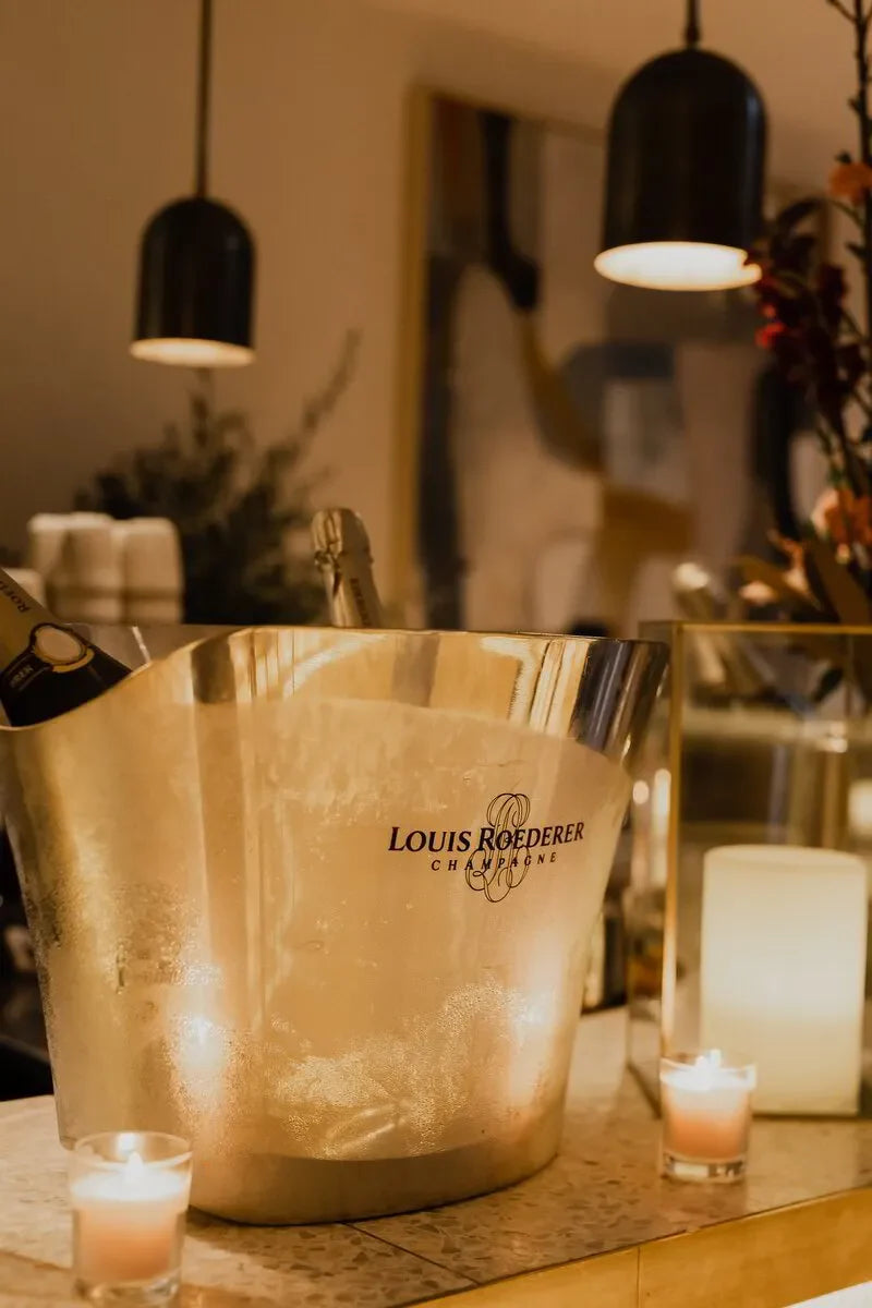 Louis Roederer champagne bottles in ice bucket with candles in elegant indoor setting