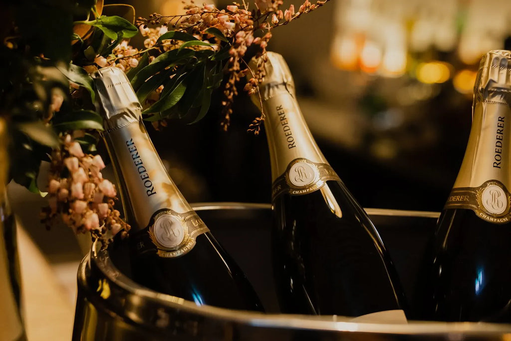 Louis Roederer champagne bottles in an ice bucket with flowers, elegant bar setting