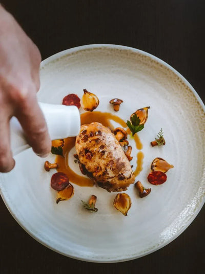 Champagne VIP tour dining: Chef pours sauce over expertly plated dish with mushrooms, onions, and sausage. Sold out.