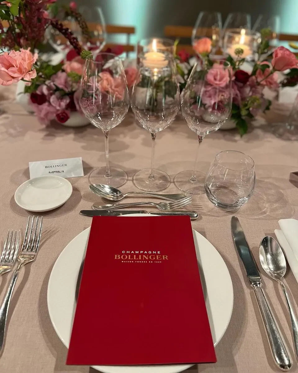 Bollinger Champagne VIP Tour place setting. Includes Champagne Bollinger menu, elegant glassware & flowers. June 2026 (Sold