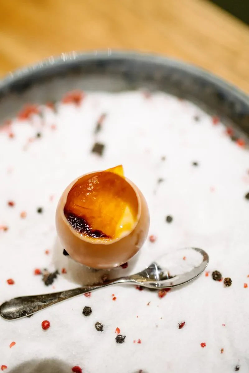 Gourmet dessert served in an eggshell with caramelized top, on a plate with scattered spices