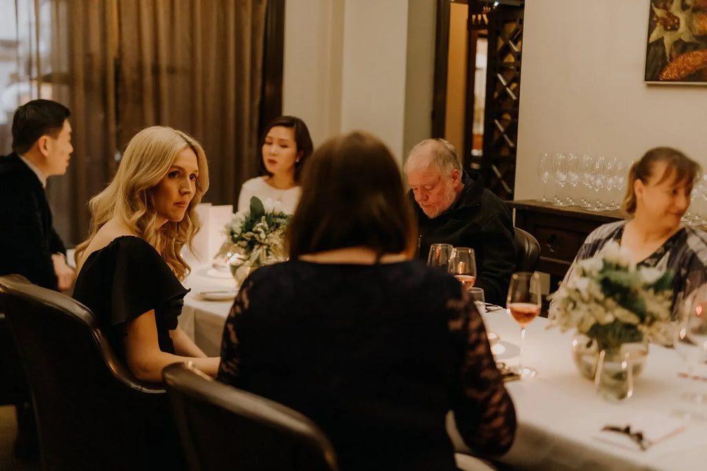 Elegant dinner party in Adelaide with six people, wine glasses, and floral centerpieces