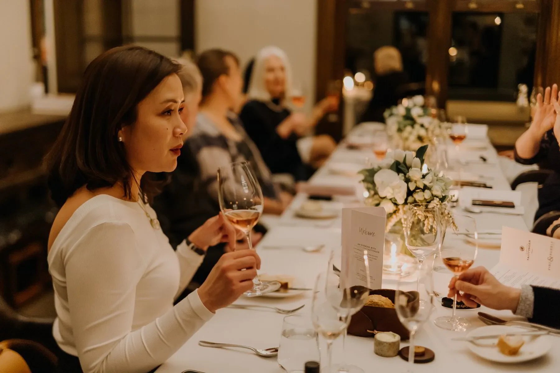 Elegant dinner party with guests toasting wine at a decorated table with white flowers